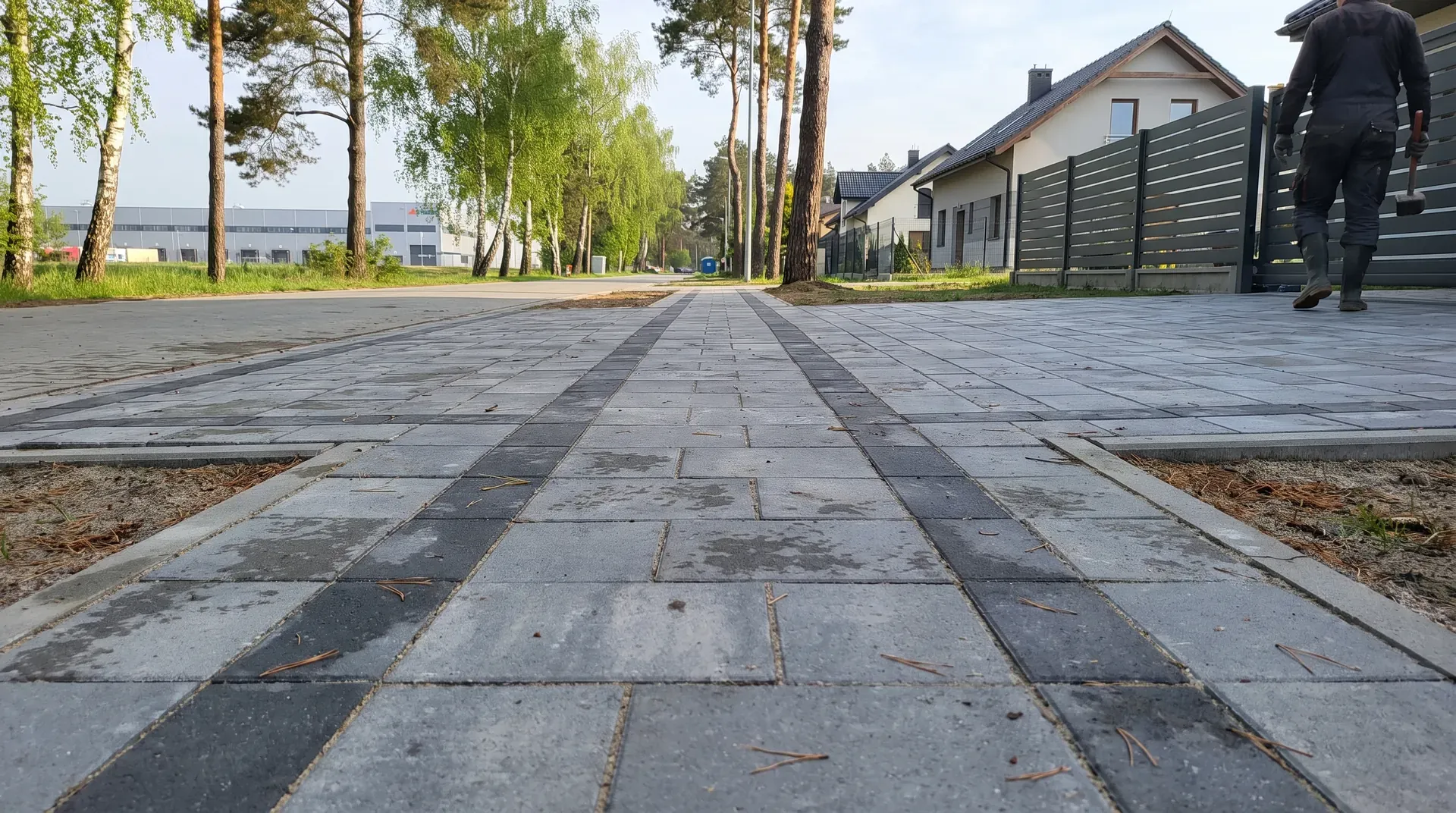 Plac z szarej kostki brukowej przy hali magazynowej i domach w Nadarzynie