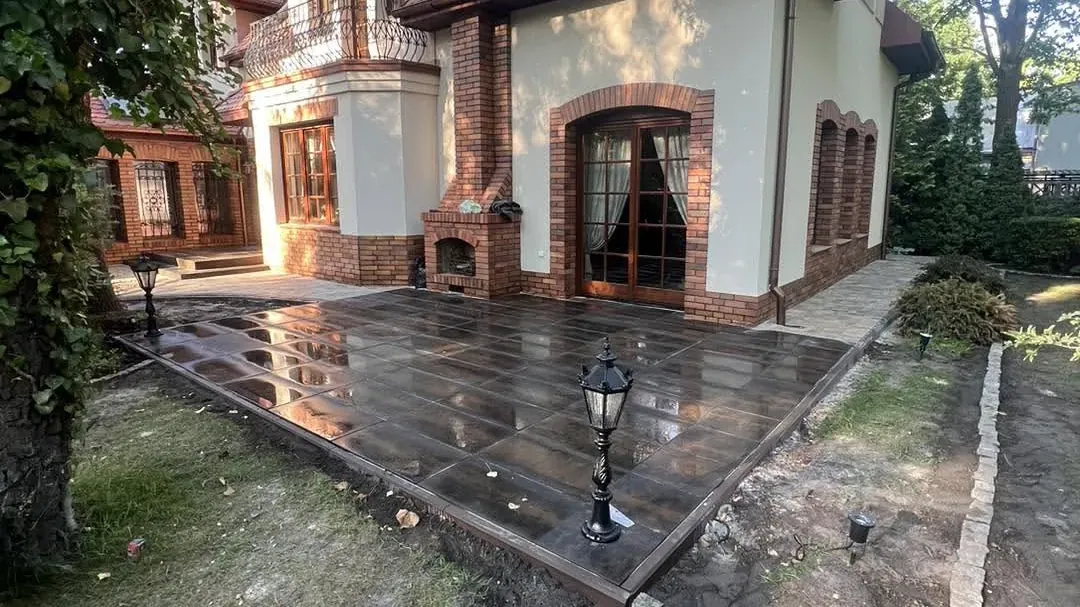 Taras z płyt przy domu jednorodzinnym ze spadkiem w stronę ogrodu
