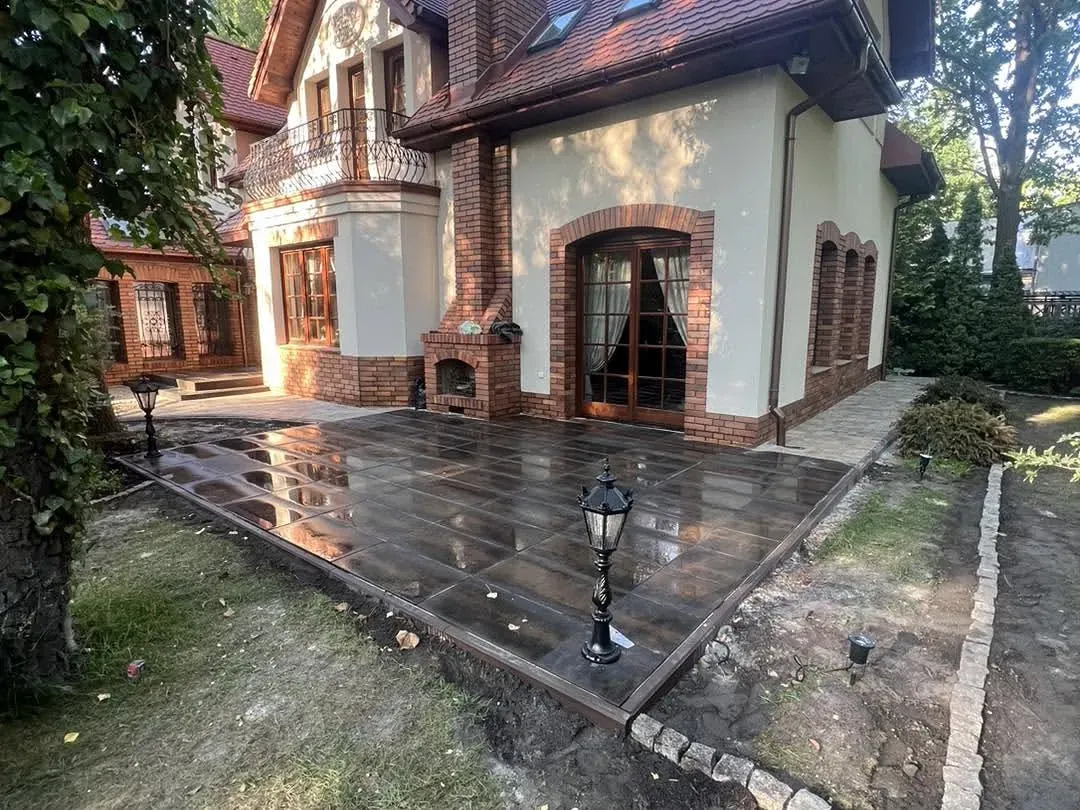 Taras z ciemnych płyt gresowych z obrzeżem z kostki granitowej przy domu