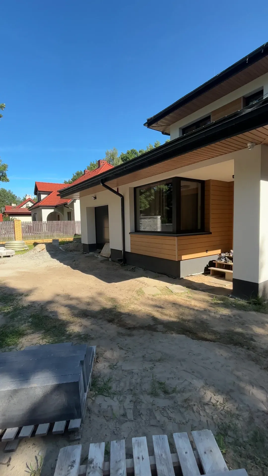 Przed: Wejście do domu: piaszczysty teren przed pracami i nawierzchnia z kostki płytowej ze schodami w trakcie realizacji