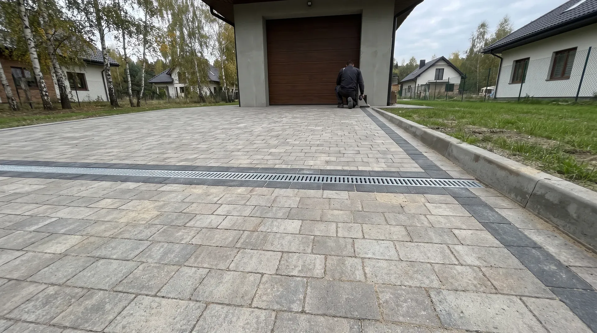Podjazd z szarej kostki przed domem jednorodzinnym w Łomiankach